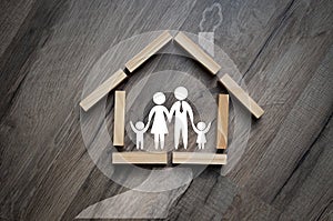 House made of wooden pieces with family stick figures on wooden background metaphor for dream of home ownership photo