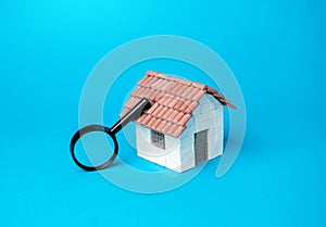 House and magnifying glass. Searching for real estate to buy.