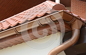 House metal rooftop with plastic rain gutter pipeline, soffit and soffit boards. Guttering house roof corner with downspout pipe