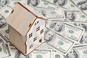 House model on background of U.S. one hundred dollar bills. Property investment, home loan, house mortgage, real estate concept