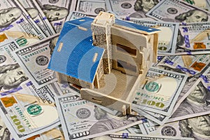 House model on background of U.S. one hundred dollar bills. Property investment, home loan, house mortgage, real estate concept