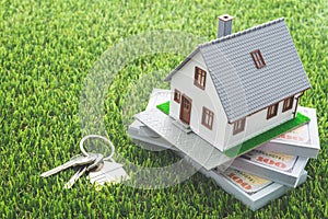 House model, bill dollar banknotes and key on green artificial grass background. Money saving for new house, home loan
