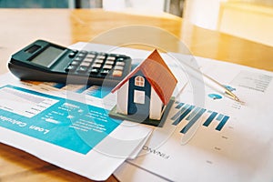 House model,Calculator and financial chart  on wooden table. Investment to buying property concept