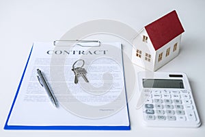 House model, calculator and house key lying on real estate contract, home loan and investment concept