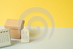 House model and calendar on gray and yellow background. Real estate house rent sell buy concept