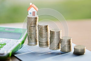 House model on coins stacks with calculator as background. Concept for property ladder, mortgage and real estate investment.