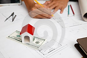 House model on dollar banknote and blueprint with architecrt in office. Real estate concept. Home construction financing photo