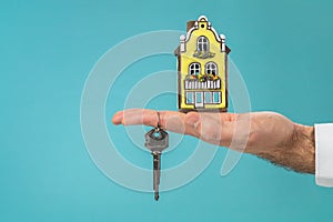 House model and key in hand, real estate concept, turquoise color copy space