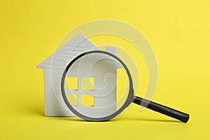 House model and magnifying glass on background. Search concept