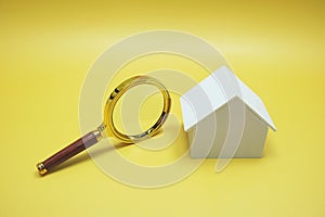 House model and Magnifying glass isolated on yellow background