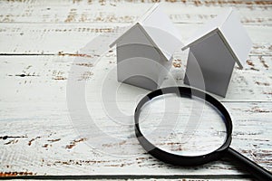 House model and magnifying glass on wooden background