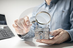 House model with man holding magnifying glass home inspection or searching for a house