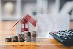 House model and money coins saving for concept saving money for buying a house, investment mortgage finance, and home loan