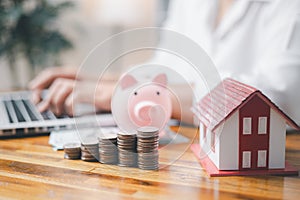 House model and money coins saving for concept saving money for buying a house, investment mortgage finance, and home loan