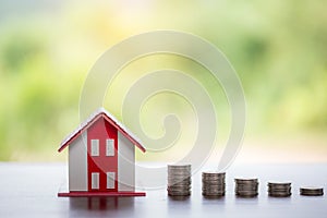 House model and money coins stacks with blur nature background. Savings plans for home, loan, investment, mortgage, finance and