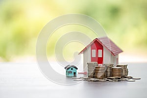 House model and money coins stacks with blur nature background. Savings plans for home, loan, investment, mortgage, finance and