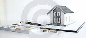 House model and Money, house key lying on real estate contract, home loan and investment concept