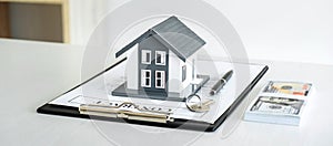 House model and Money, house key lying on real estate contract, home loan and investment concept