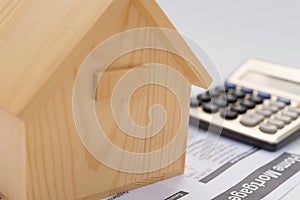 House model and mortgage paper file with a calculator