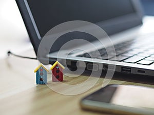 House model plastic color red and blue, mini object on wooden table, Blurred of notebook and mobile phone background