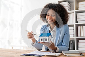 House model with real estate agent and client discussing home insurance contract Or the real estate loan