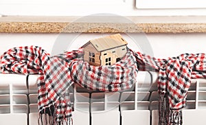 House model and scarf on radiator. Home. Winter. Energy. Efficiency. Heating