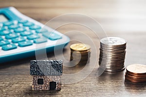 House model, stack of coins and calculator. Concept in house selling, buying, loan and finance business.