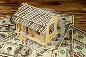 House model and U.S. one hundred dollar bills on wooden background. Property investment, home loan, house mortgage, real estate