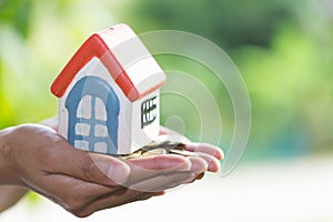 House models and coin in human hands, Mortgage concept by money