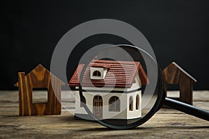 House models and magnifying glass on table. Search concept