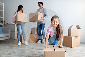 House moving concept. Young family of three relocating and unpacking boxes in new flat indoors