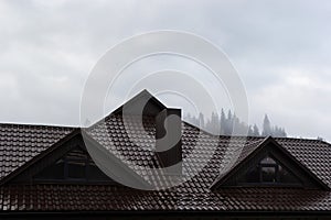 House with new brown metal tile roof and rain gutter. Metallic Guttering System, Guttering and Drainage Pipe Exterior