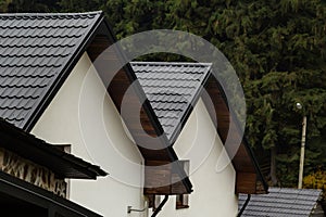 House with new brown metal tile roof and rain gutter. Metallic Guttering System, Guttering and Drainage Pipe Exterior