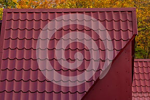 House with new brown metal tile roof and rain gutter. Metallic Guttering System, Guttering and Drainage Pipe Exterior