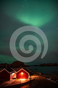 House in Norway at night under the sky with Aurora Borealis and clouds