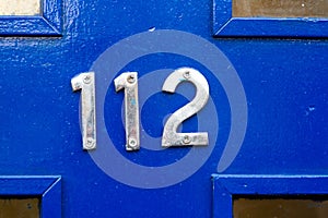 House number 112 on a blue wooden front door