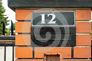 House number 12 above letterbox in red fence
