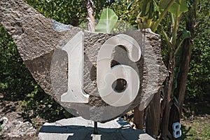 House number 16 installed on a big rock in the garden of residence