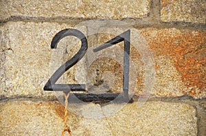 House number 21 on rustic sandstone brick wall, rusty wrought iron metal numbers