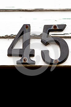 House number 45 in black on a white wooden house wall