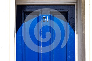 House number 51 on a royal blue wooden front door with vertical lines in London