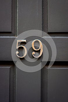 House number 59 on a gray wooden front door