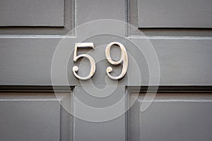 House number 59 on a gray wooden front door