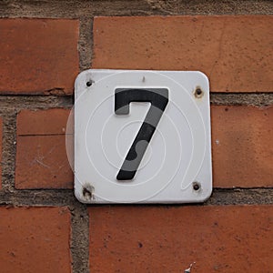 House number "7" attached to a brick wall