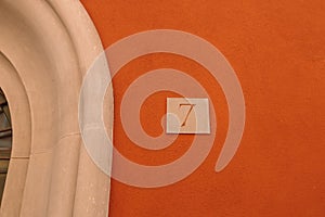 House number 7 over brick sunny orange wall. Houses with personality concept