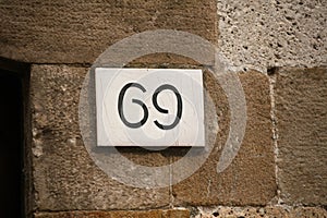 House number on brick old wall. Sexy 69 license plate on the wall of ancient building. Yin yang concept