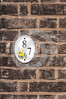 House number eighty seven mounted on a brick wall