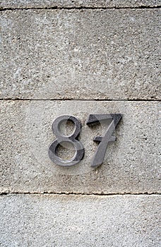 House number numerals on a concrete wall. Number 87 decorative types, close up, no people