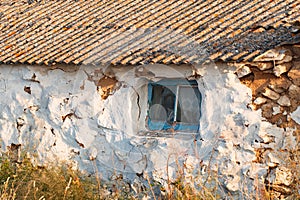 House old ruined abandoned askew one - storey with window, cracked plaster