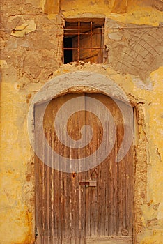 A house with old wooden door and metal steel window at the top at seaside waterfront fishing village of Marsaxlokk, Malta